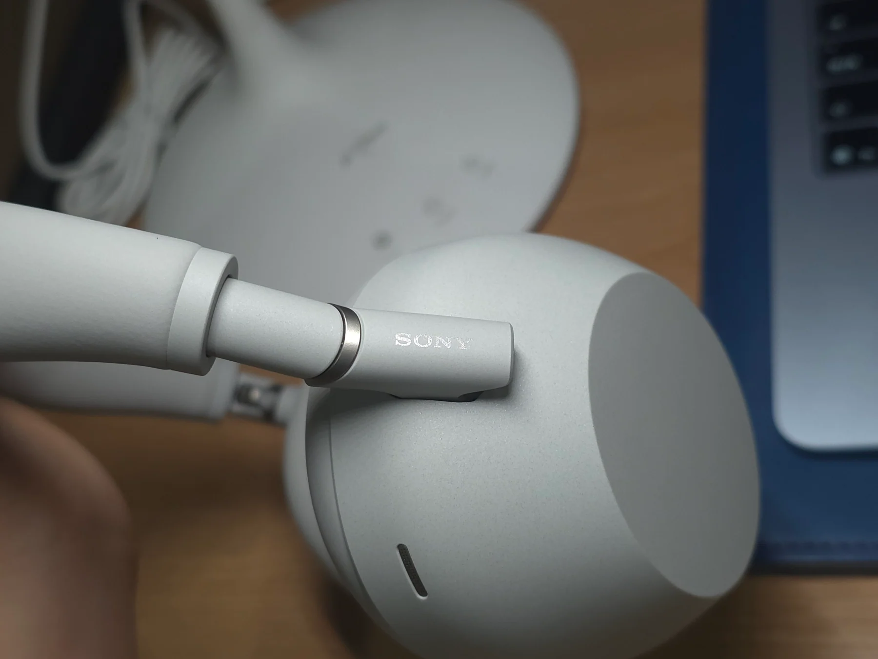 밝은 색 Sony WH-1000XM6 헤드폰의 힌지와 SONY 로고를 가까이 촬영한 사진